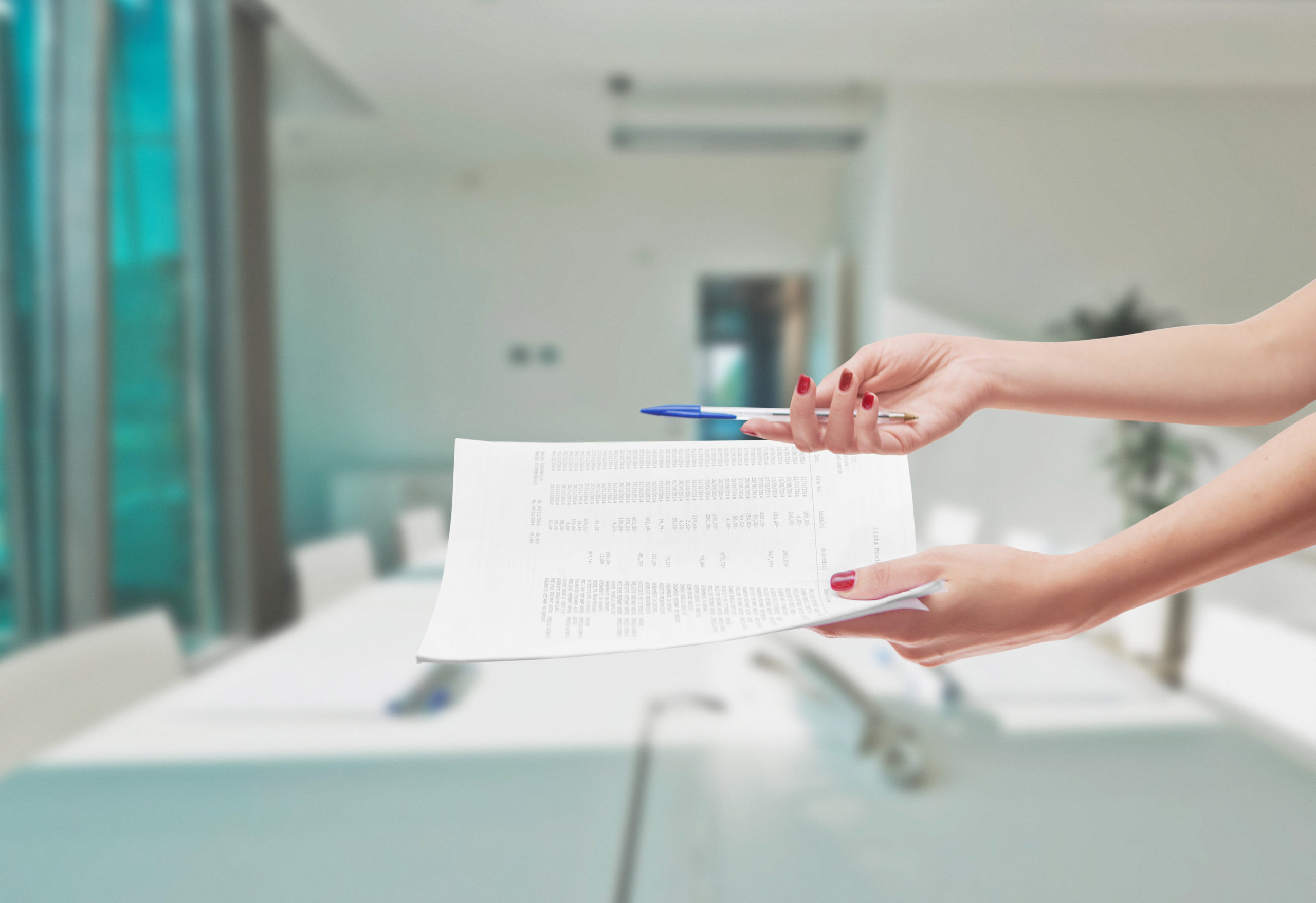 hand holding a pen and papers that needs to be signed